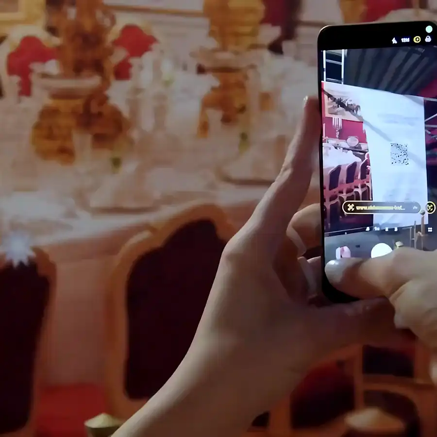 A visitor holds a phone over the imperial banquet table at the Sisi Museum and the scene comes alive in augmented reality