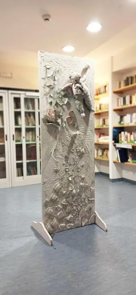 Pamela Mattana's white plaster door installation with ceramic shards and a doll, standing in a library